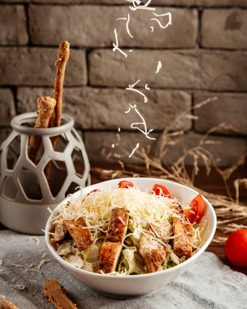 cheese pouring on caezar salad side view